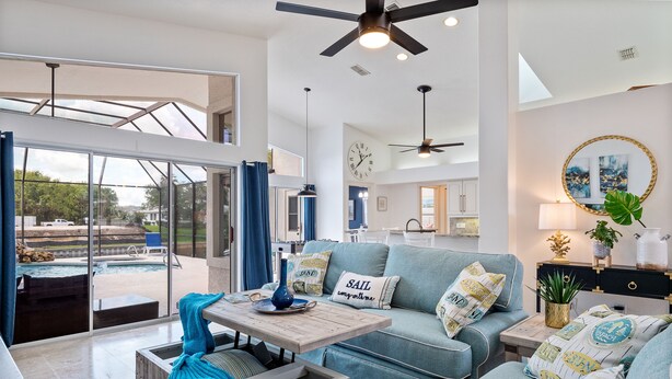 A spacious living room with a large glass door leading to an outdoor area, a ceiling fan, and a clock on the wall. - Waterfront Home with Pool,  Hot Tub, Dock, Game Room & 10 minutes to the Beach (Palm Coast)