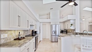 A modern kitchen with white cabinetry, stainless steel appliances, and a marble countertop. - Waterfront Home with Pool,  Hot Tub, Dock, Game Room & 10 minutes to the Beach (Palm Coast)