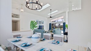 A dining area with a large table set for six, a chandelier, and a view of the living room. - Waterfront Home with Pool,  Hot Tub, Dock, Game Room & 10 minutes to the Beach (Palm Coast)