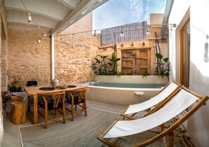 A cozy outdoor seating area with a wooden table and chairs, a hammock, and a stone wall backdrop. - Design house with swimming pool near the beach (València)