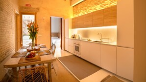 A modern kitchen with white cabinets, a wooden countertop, and a built-in oven. There is a dining area with a table set for two and a vase of flowers. - Design house with swimming pool near the beach (València)