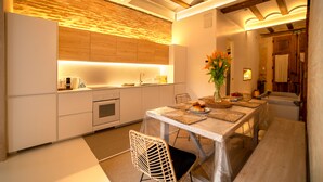 A modern kitchen with wooden beams, a built-in oven, and a dining area with a table set for two. - Design house with swimming pool near the beach (València)