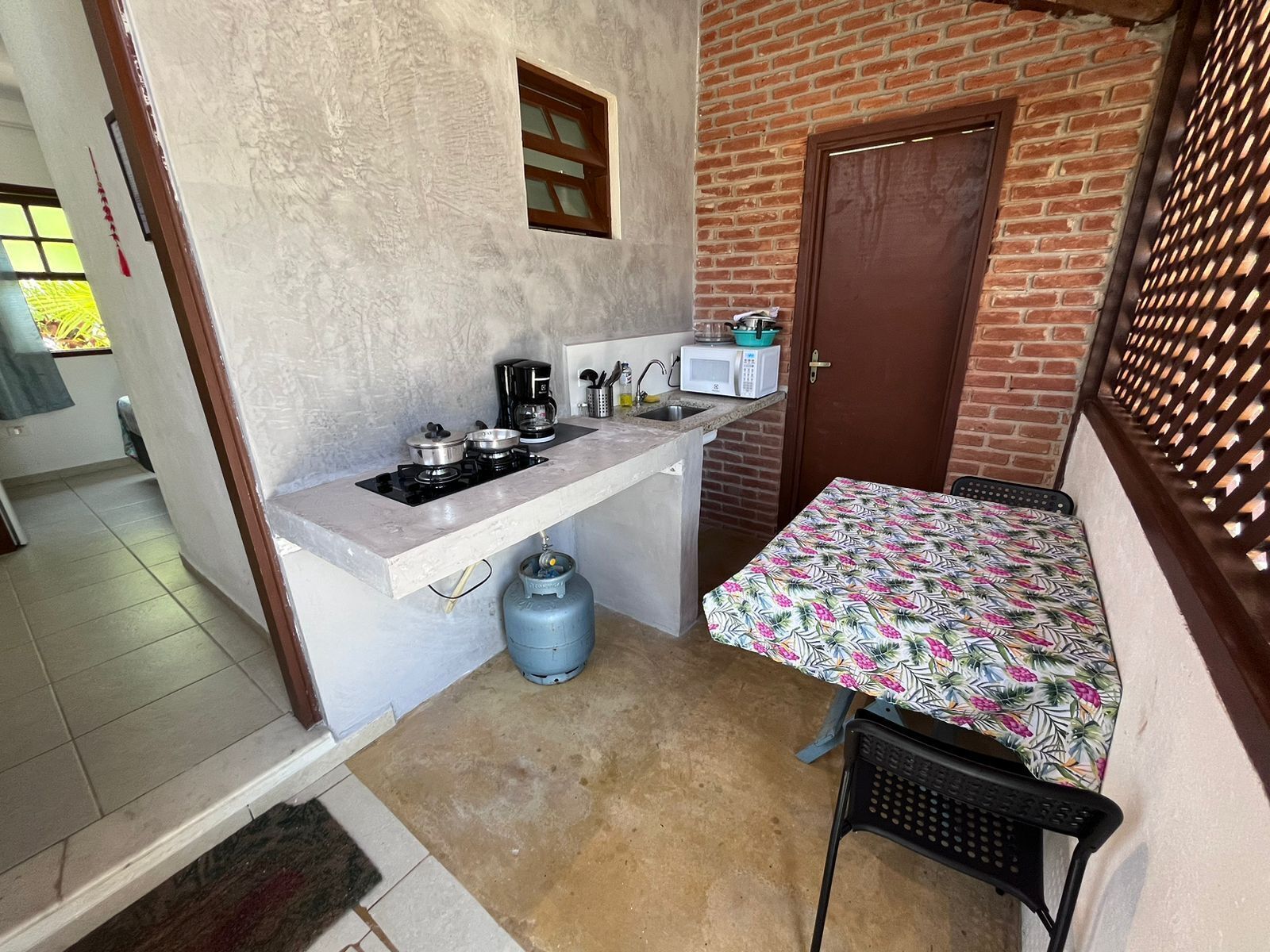 A compact kitchen with a gas stove, a microwave, and a small table with a floral tablecloth.