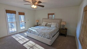A bedroom with a bed, ceiling fan, two bedside tables, and a window with blinds. - Cedar Lake Retreat (Buckhead)