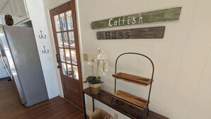 A hallway with a wooden bench, a wall-mounted shelf with baskets, and a door with a frosted glass panel. - Cedar Lake Retreat (Buckhead)