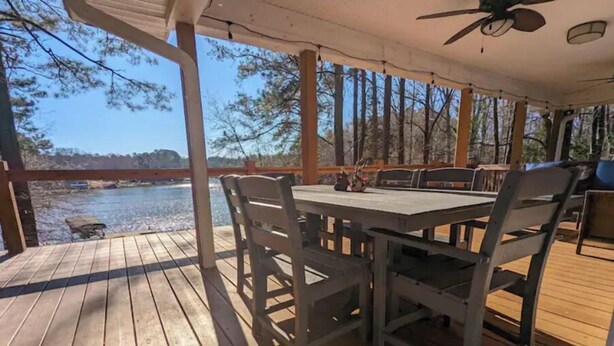 A wooden deck with a table and chairs, overlooking a body of water and trees. - Cedar Lake Retreat (Buckhead)