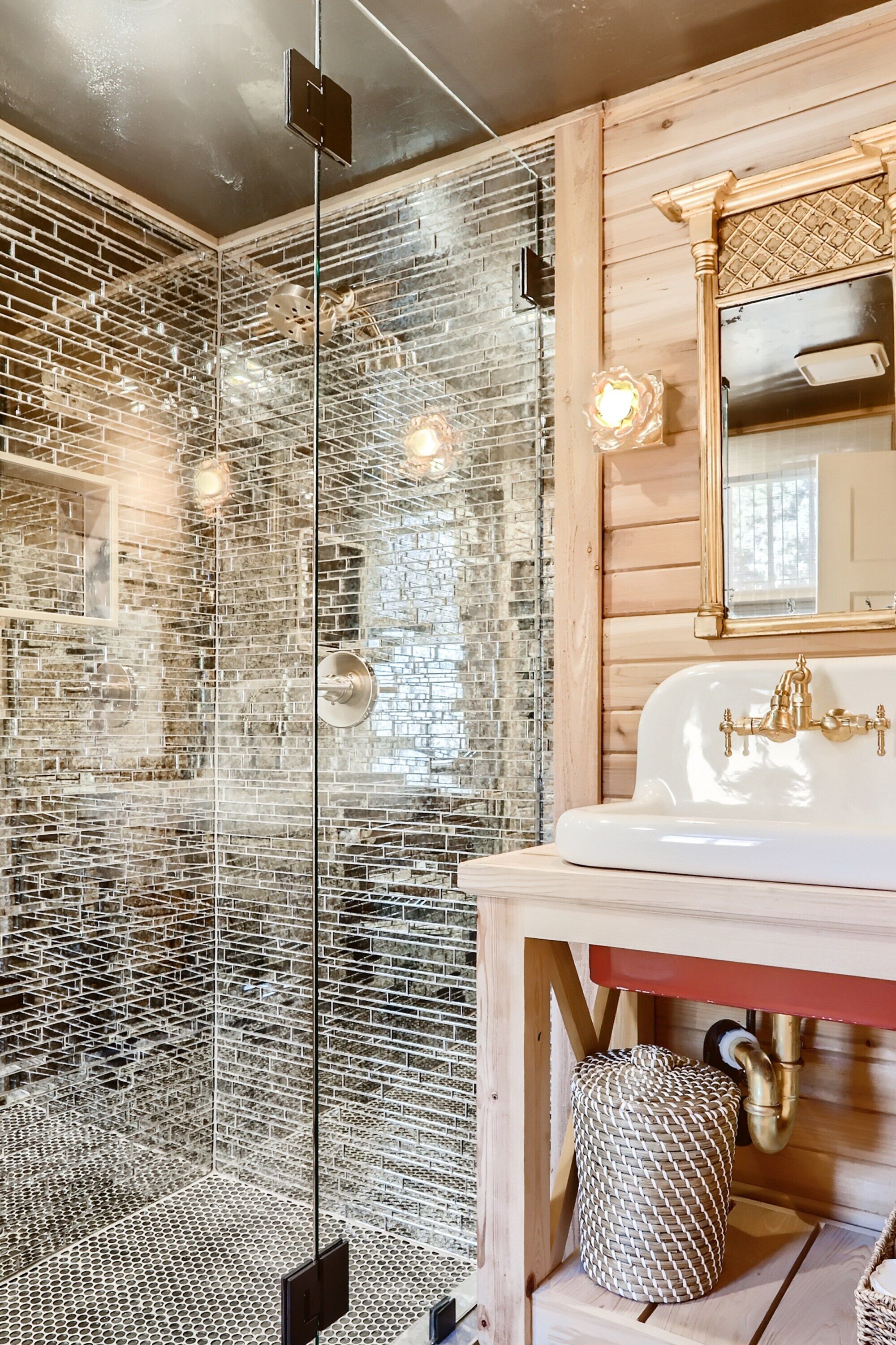 Une salle de bain avec une douche à parois de verre, un meuble-lavabo en bois avec un lavabo blanc et un miroir au-dessus du lavabo.