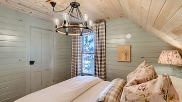 Quarto com cama, lustre, cortinas xadrez, janela e abajur.