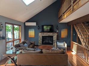 A spacious living room with a fireplace, a large sofa, and a television.