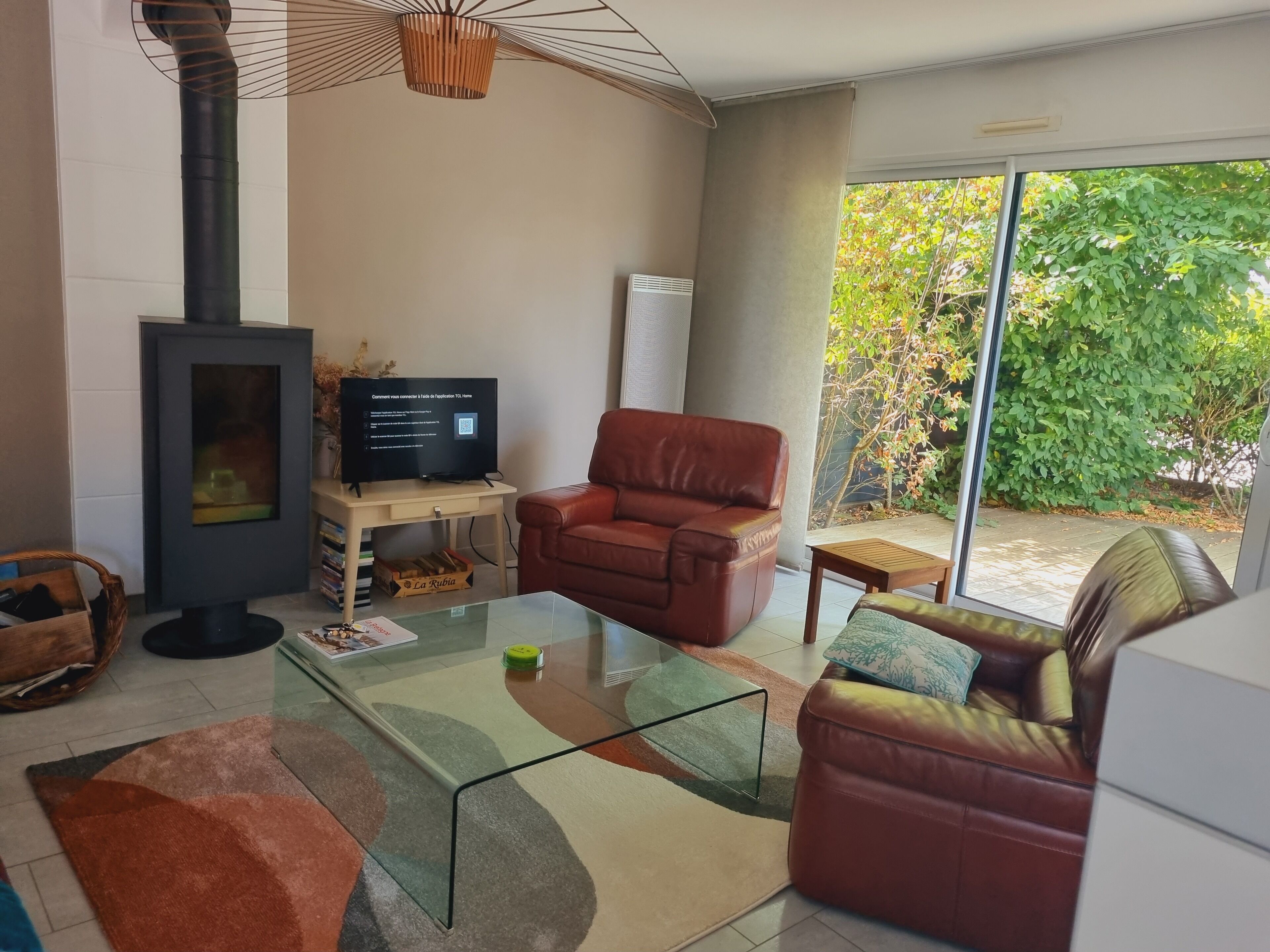 A living room with a fireplace, a television, leather sofas, and a glass coffee table.