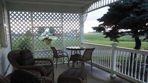 A covered porch with wicker furniture, a table, and chairs. - Country View Lodging In the heart of Amish Country (Baltic)
