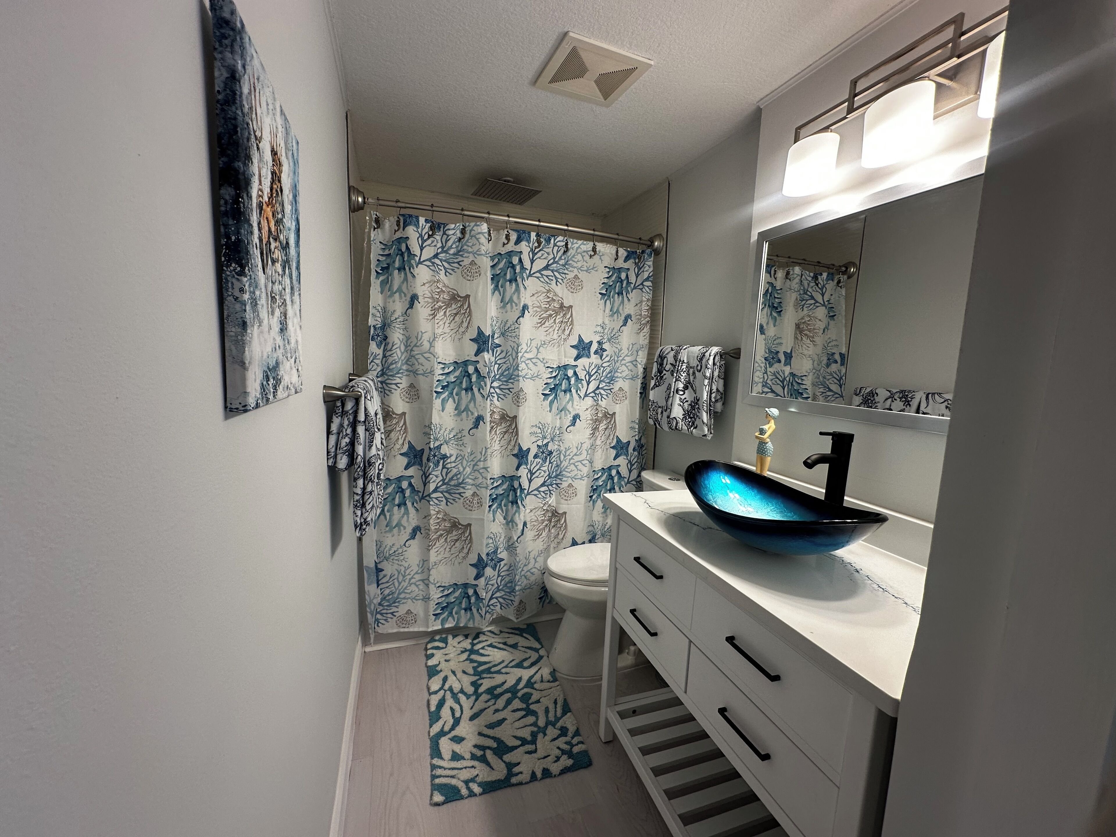 Ein Badezimmer mit Duschvorhang, Toilette, Waschbecken und Spiegel.