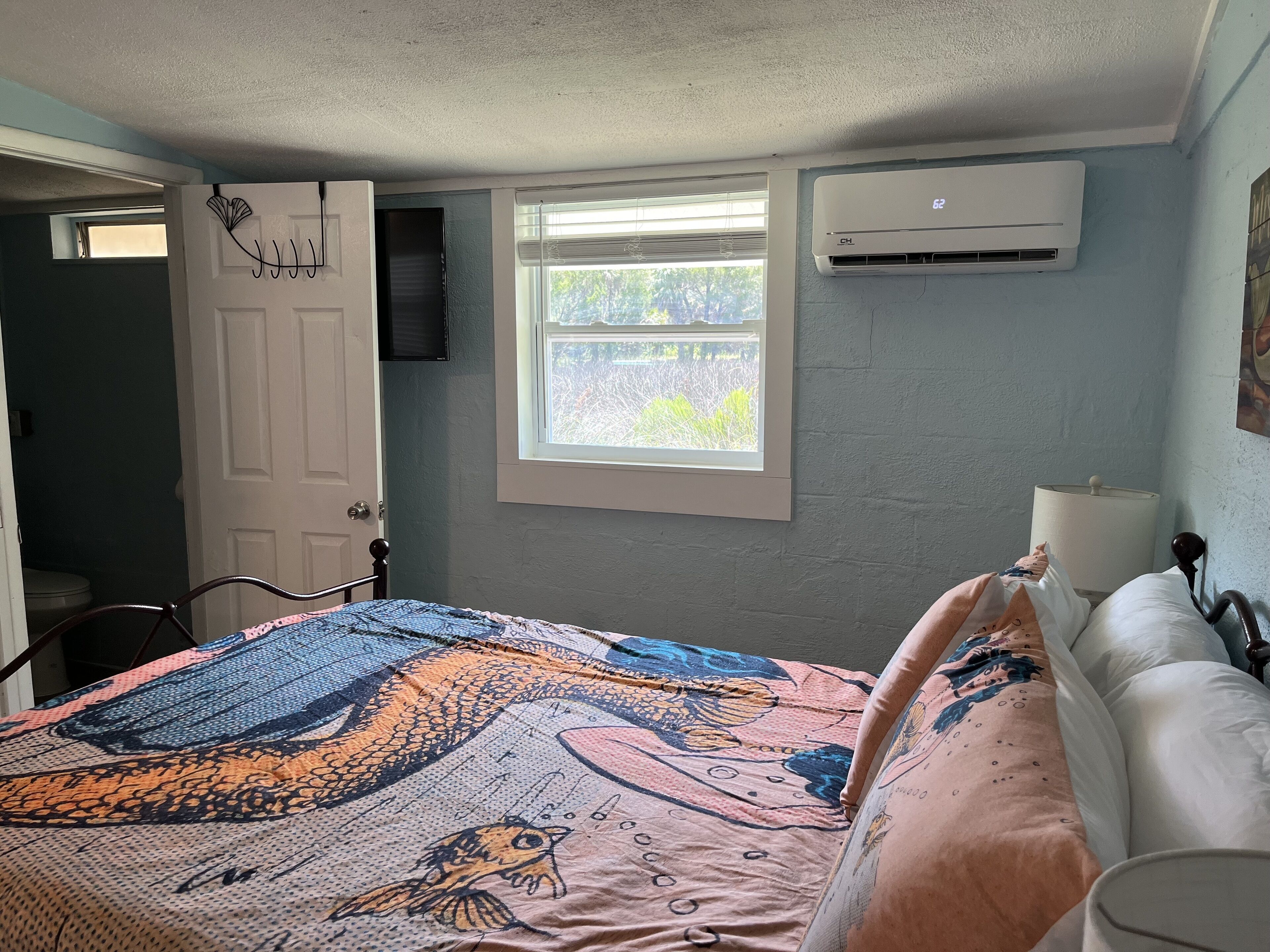 Ein Schlafzimmer mit Bett, Fenster, Klimaanlage und Tür.