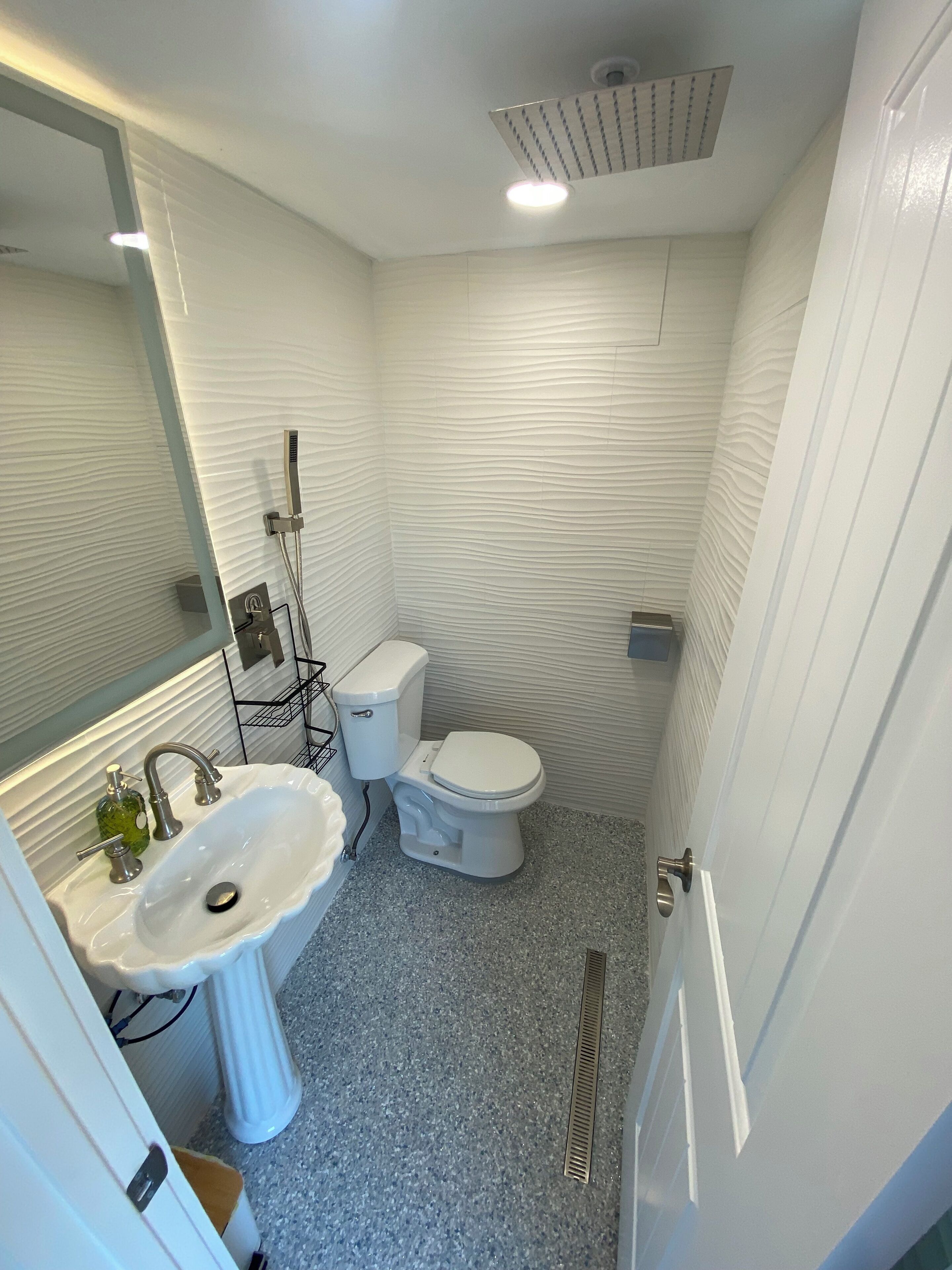 A bathroom with a white sink, toilet, and shower.