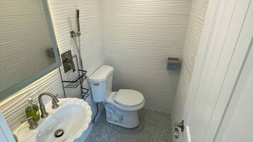 A bathroom with a white sink, toilet, and shower.