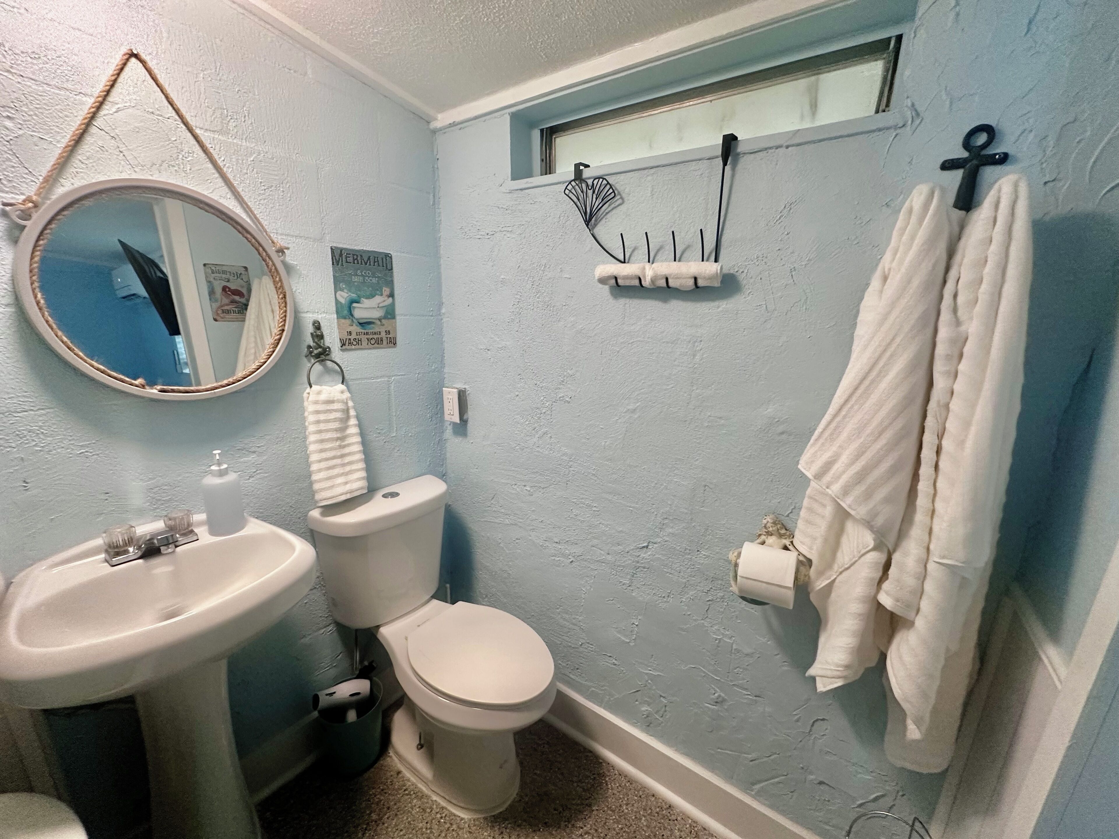 A bathroom with a sink, toilet, and a mirror. There is a towel rack with a towel hanging on it.