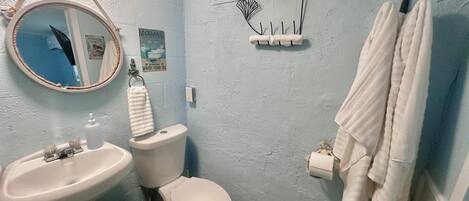A bathroom with a sink, toilet, and a mirror. There is a towel rack with a towel hanging on it.