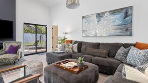 Ein modernes Wohnzimmer mit einem grauen Sofa, einem gemusterten Sessel und einem Couchtisch mit Tablett.