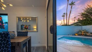 Ein modernes Interieur mit Essbereich, einem großen Spiegel und Blick auf einen Pool bei Sonnenuntergang.