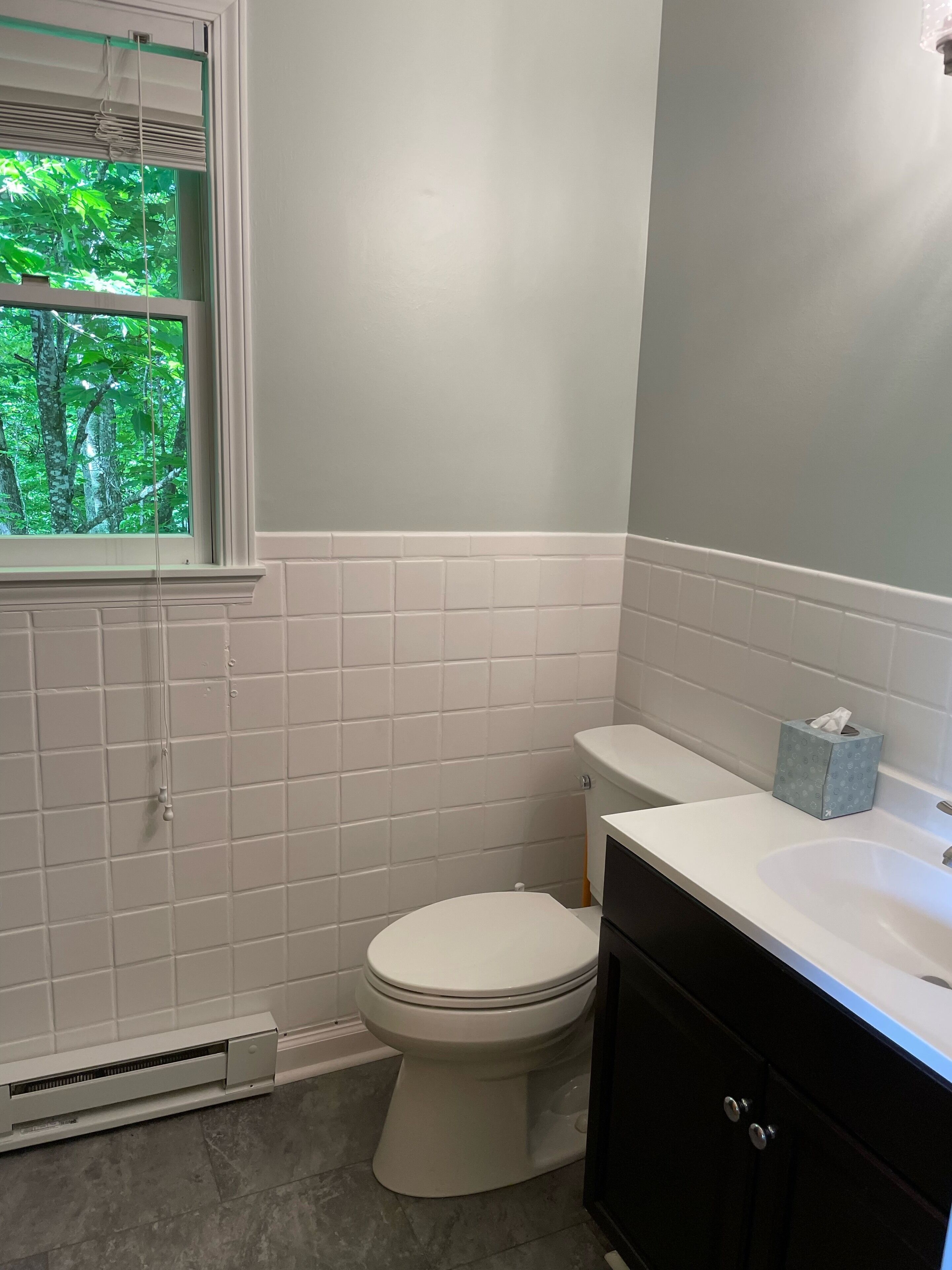 Un baño con inodoro, lavamanos y ventana con persianas.