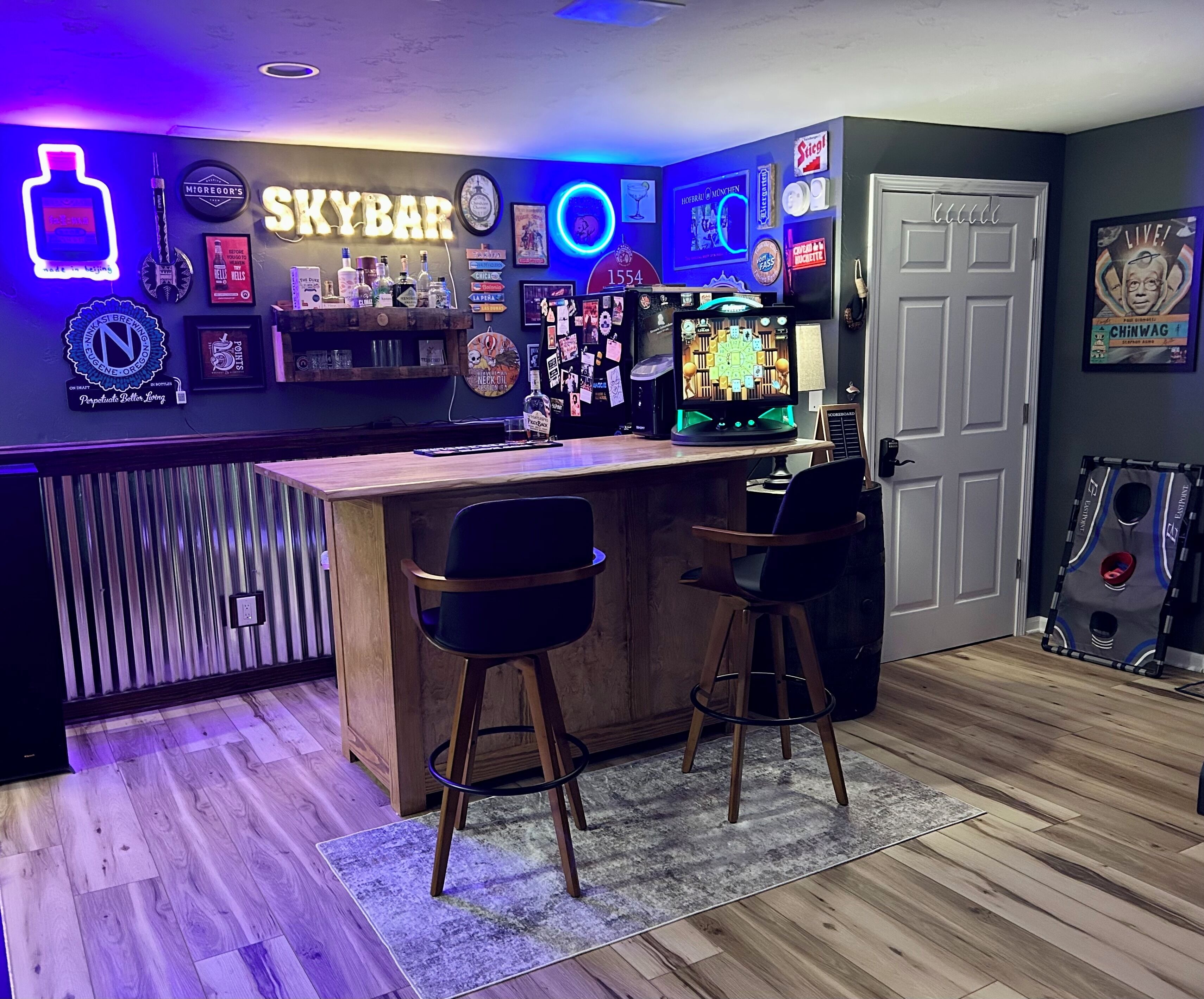 A bar area with a neon sign reading "SKYBAR," various framed pictures, and a dartboard.