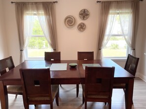 A dining room with a rectangular table, six chairs, and three wall-mounted decorative plates. - Large , CLEAN townhome with pool view, next to Sports Complex (Panama City Beach)