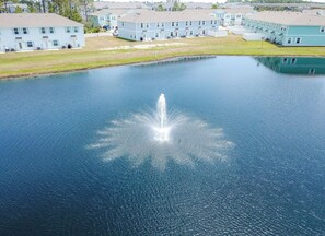 A large body of water with a fountain in the center, surrounded by light blue buildings. - Large , CLEAN townhome with pool view, next to Sports Complex (Panama City Beach)