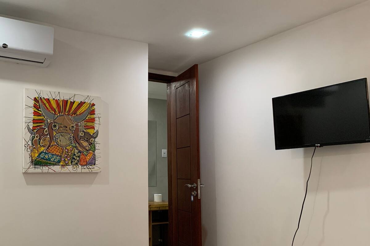 A room with a wall-mounted TV, a door, and a colorful artwork.