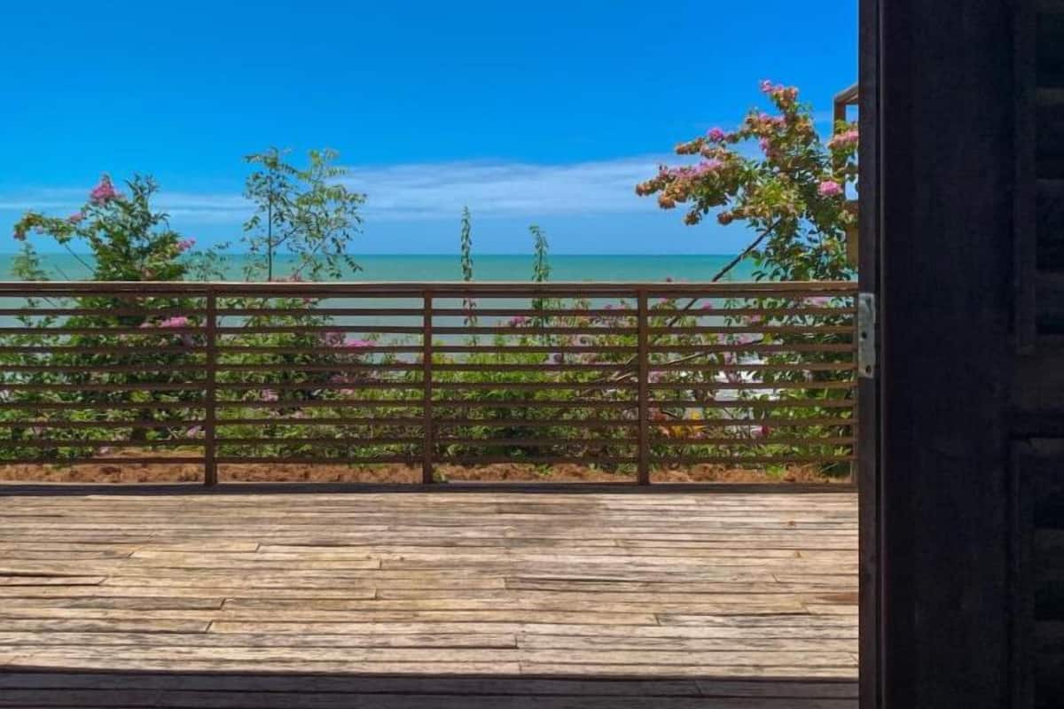 A wooden deck with a view of the ocean and a metal railing.