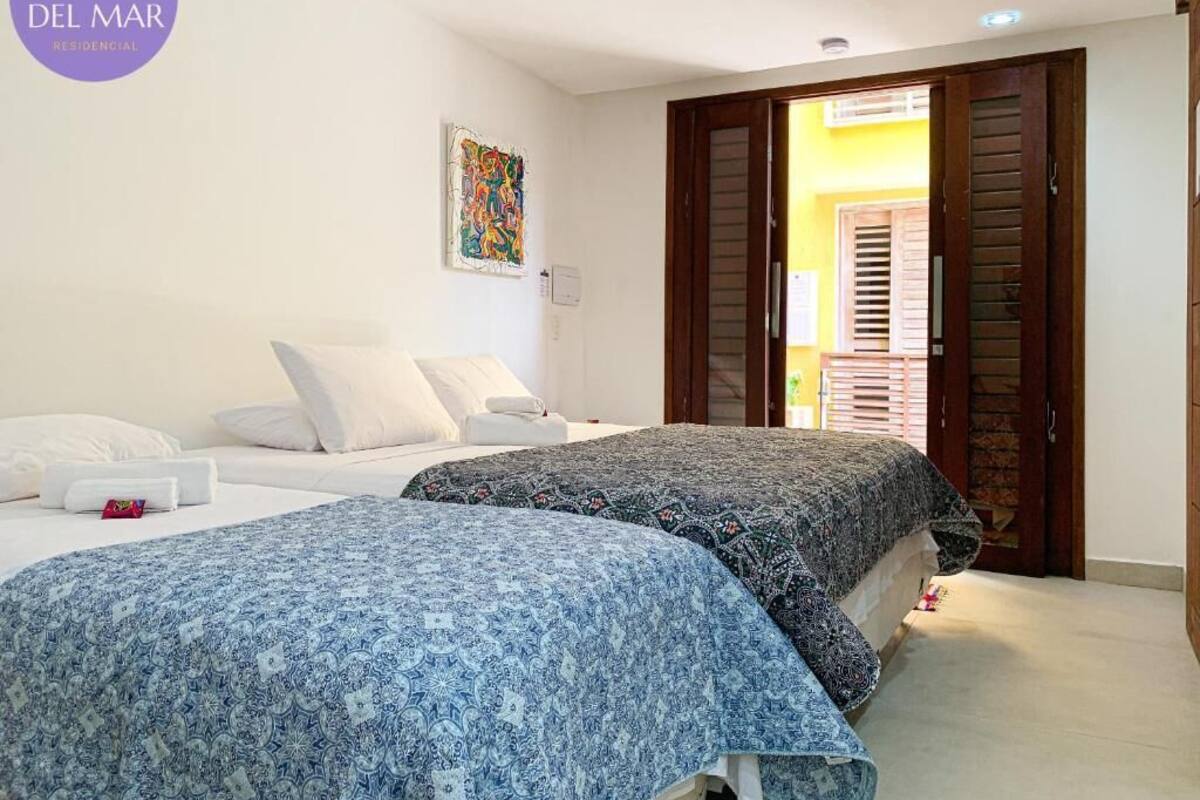 A bedroom with two beds, a painting on the wall, and a wooden door leading to another room.