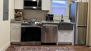 A modern kitchen with white cabinets, stainless steel appliances, a microwave, stove, oven, dishwasher, and a refrigerator. - Breathtaking Views!  (Matlacha)
