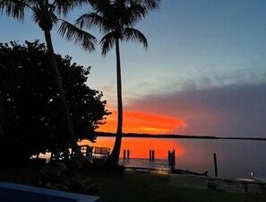 A sunset view with palm trees and a dock extending into calm water. - Breathtaking Views!  (Matlacha)