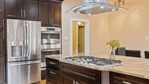 A modern kitchen with stainless steel appliances, dark cabinetry, and a marble countertop. - 2x Properties + Pool + Pet Friendly (Lakeland)
