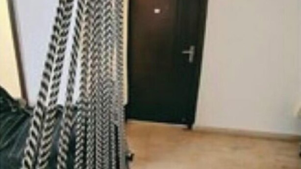 A room with a hammock bed, a door, and a wooden floor.