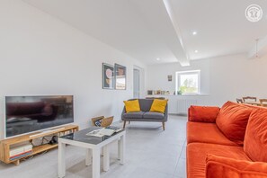 Relax in this stylish living room with a flat-screen TV, comfortable sofa, and bookshelf.