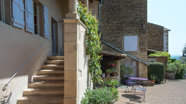 Una escalera de piedra que lleva a un edificio con un área de estar al aire libre techada.