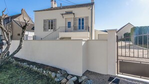 A two-story house with a balcony, a gated driveway, and a small garden area. - Le Clos de Lescargot (DEMIGNY)