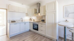 A modern kitchen with white cabinetry, a built-in oven, a microwave, and a sink. - Le Clos de Lescargot (DEMIGNY)