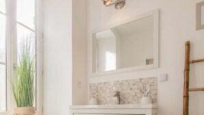 A bathroom with a white vanity, a mirror, a potted plant, and a tiled floor. - Le Clos de Lescargot (DEMIGNY)