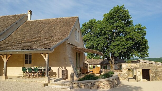 A rustic building with a tiled roof, a covered patio with outdoor seating, and a stone wall garden. - Une Pause à Outry - Ozenay (OZENAY)
