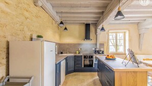 A kitchen with a built-in oven, a sink, and a stove. There is a window providing natural light and a view of the outdoors. - Une Pause à Outry - Ozenay (OZENAY)