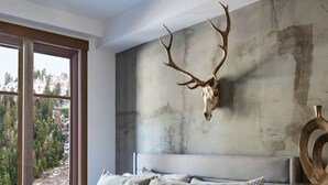 Ein Schlafzimmer mit einem großen Bett, einer Holzkommode und einem an der Wand befestigten Hirschschädel.