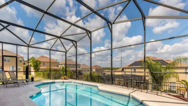An indoor swimming pool with a clear view of the sky and surrounding buildings.