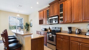 A kitchen with wooden cabinets, a central island, stainless steel appliances, and a window with blinds.