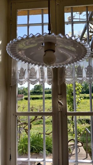 A window with a decorative lace curtain, a metal gate, and a view of a garden.