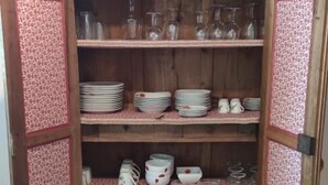 Un aparador de madera con varios estantes, algunos con cristalería y platos.