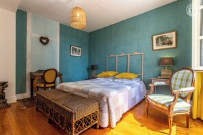 A bedroom with a bed, a chair, a bench, a table, and a lamp. - Aux 3 Marronniers – MERCUREY (MERCUREY)
