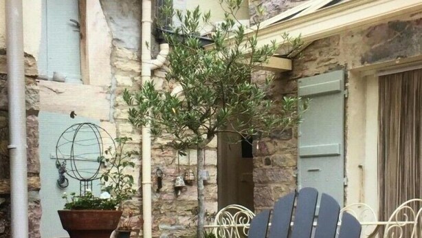 Un espace patio aménagé avec une chaise et une table, entouré de murs en pierre et de plantes en pot.