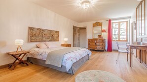 A bedroom with a bed, bedside tables, a dresser, a chair, and a window.