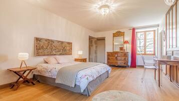 Een slaapkamer met een bed, nachtkastjes, een dressoir, een stoel en een raam.